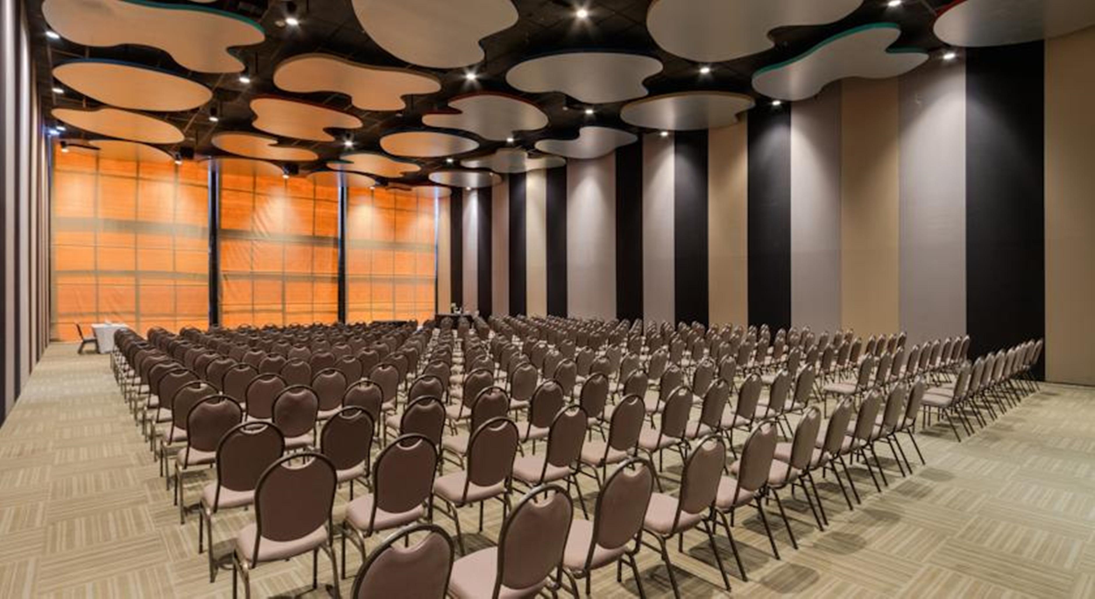 Royal Tulip Brasilia Alvorada Hotel Ngoại thất bức ảnh The photo shows a large conference or event space filled with numerous empty chairs arranged in rows. The chairs have a simple design, with cushioned seats and backs. The walls of the room are decorated with a combination of dark and light tones, and