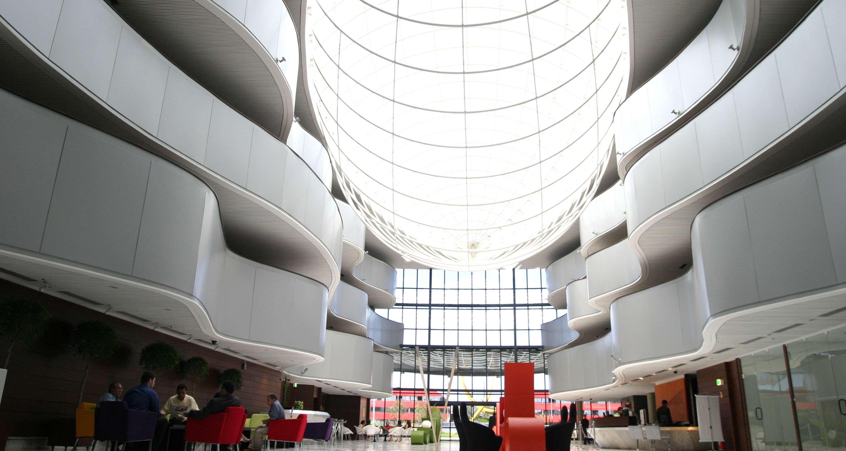 Royal Tulip Brasilia Alvorada Hotel Ngoại thất bức ảnh The photo depicts a modern interior space characterized by sleek, curvilinear architecture. The ceiling features a large, dome-like skylight that allows natural light to flood the area. The walls display a minimalist design with smooth, white surface